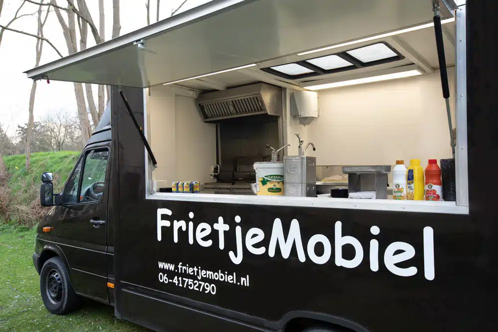 Geopende frietwagen van Frietje Mobiel met uitgiftebalie en sausflessen